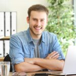 Attraktive junge Mann bei der Arbeit am Laptop im modernen Büro.