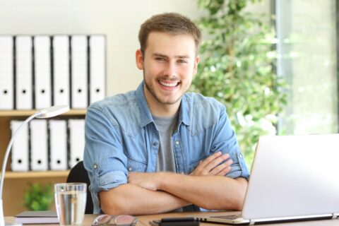 Attraktive junge Mann bei der Arbeit am Laptop im modernen Büro.