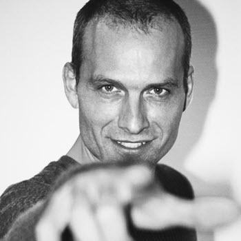 Professioneller Mann, der direkt in die Kamera lächelt, in Schwarz-Weiß aufgenommen.