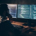 Code-Entwickler bei der Arbeit an zwei Bildschirmen, Programmierung und Softwareentwicklung.