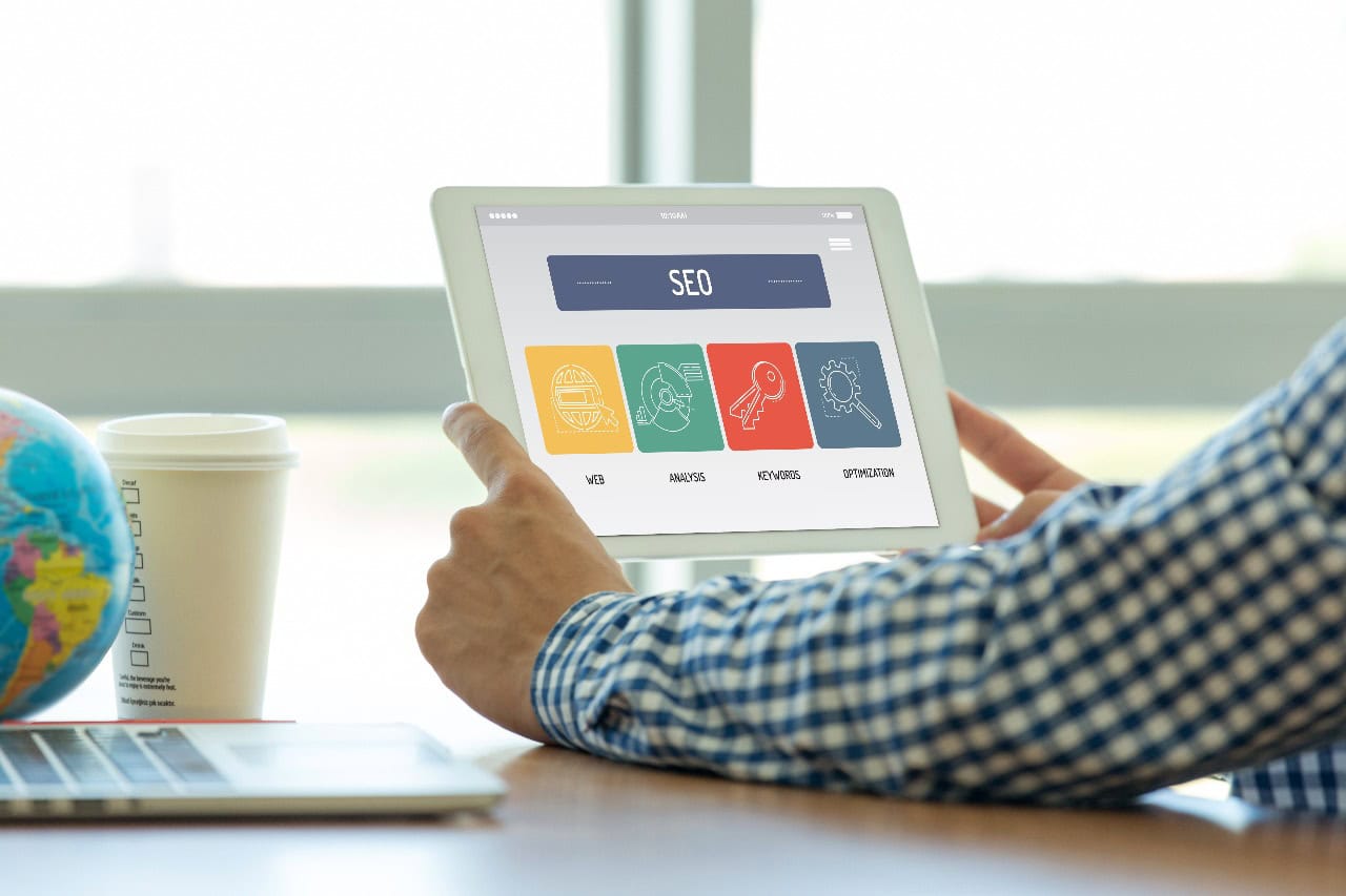 SEO-Beratung auf einem Tablet mit Symbolen für Web, Analyse, Keywords und Optimierung.