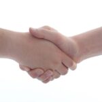Sorgfältige Handshake-Geste zwischen zwei Menschen, Symbol für Zusammenarbeit und Vertrauen.