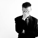 Mann im Anzug, Gesicht bedeckt, nachdenklich