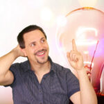 Eine Person denkt nach und zeigt auf eine Glühbirne, Symbol für kreative Ideen und Innovationen.