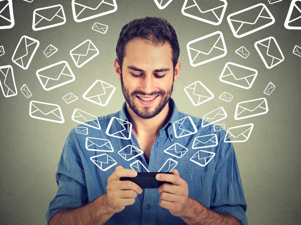Mann mit Smartphone und schwebenden E-Mail-Symbolen