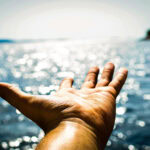 Hand über glitzerndem Wasser gehalten