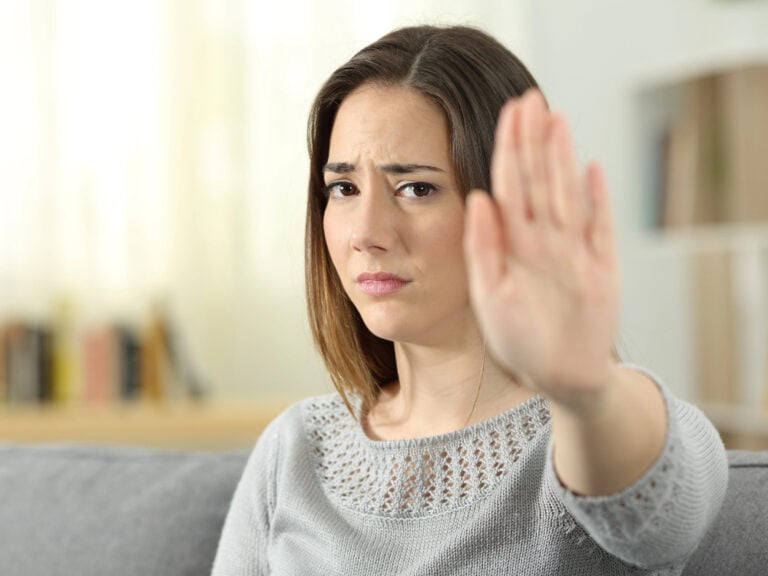 Frau mit abwehrender Handgeste im Wohnzimmer