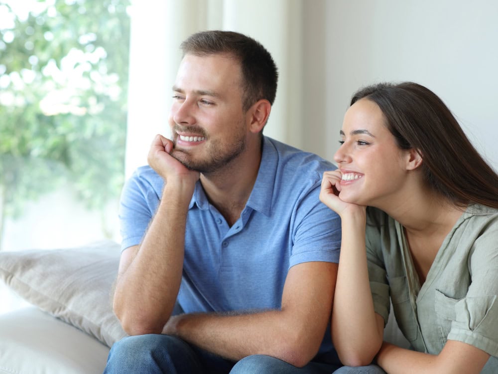 Lächelndes Paar schaut aus dem Fenster.