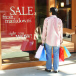 Person beim Einkaufen vor Schaufenster mit Rabatt.