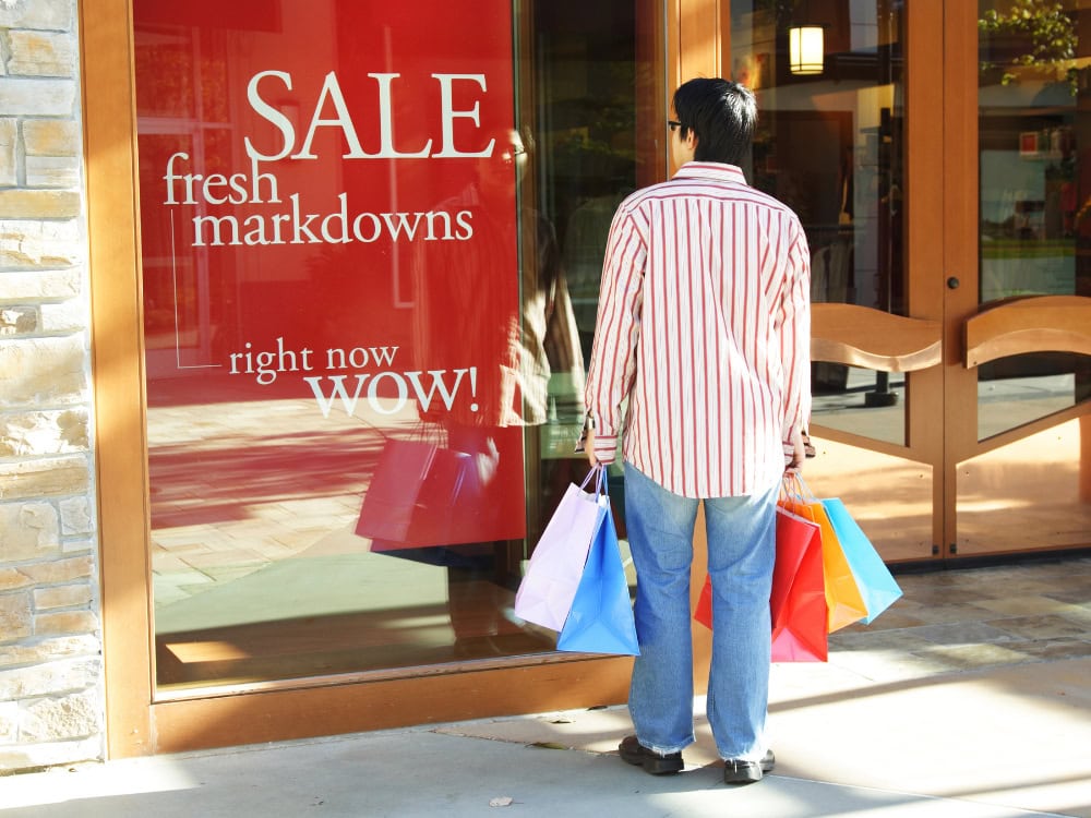 Person beim Einkaufen vor Schaufenster mit Rabatt.